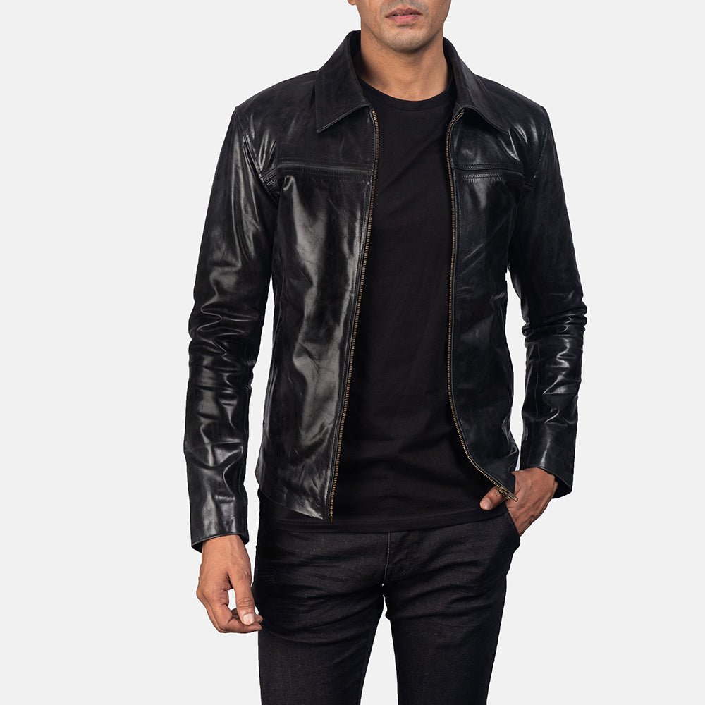 Flat-lay of black leather jacket styled with sunglasses, wristwatch, and boots on a wooden surface.